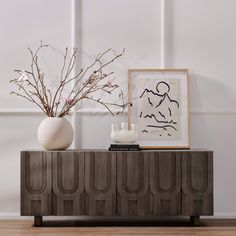 two vases sitting on top of a wooden cabinet next to a painting and plant