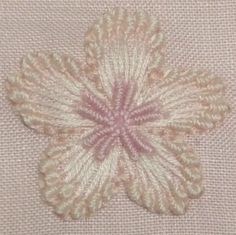 a close up of a flower on a piece of cloth with pink and white thread