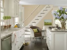 a kitchen with white cabinets and an open staircase leading up to the second floor area