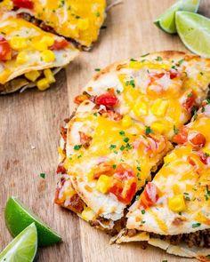 two quesadillas cut in half on a cutting board with lime wedges