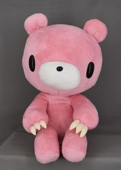 a large pink teddy bear sitting on top of a table next to a gray background