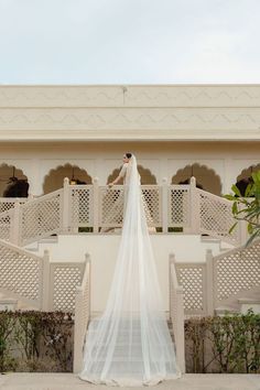 a bride and groom standing in front of a building with white balconies on it