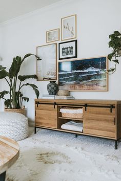 a living room with plants and pictures hanging on the wall, including a coffee table