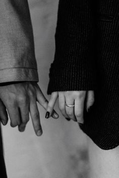 black and white photograph of two people holding each other's hands with their fingers