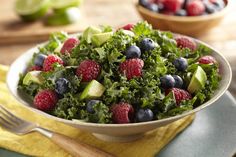 a bowl filled with greens, raspberries and avocado on top of a yellow towel