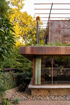 a modern house with green curtains on the windows and plants growing out of it's roof