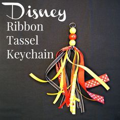 the disney ribbon tassel keychain is hanging from a black background with white polka dots