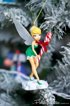 a christmas tree ornament with a tinkerbell holding a candy cane in its hand