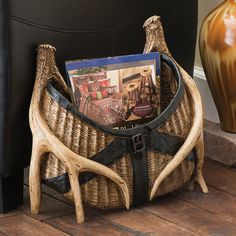 a wicker basket with magazines in it sitting on the floor next to a vase