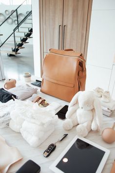 an assortment of items on a table in front of a purse, tablet and cell phone