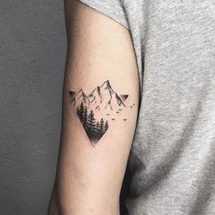 a man's arm with a mountain and pine tree tattoo on the left upper arm