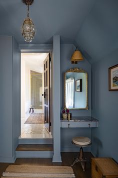 a hallway with blue walls and wooden flooring is pictured in this image from the doorway