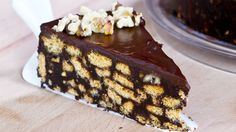 a piece of cake with chocolate and nuts on it sitting on a table next to a plate