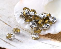 some silver and gold colored beads on a white plate