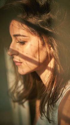 a close up of a woman's face with the sun shining through her hair