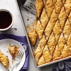 a pan filled with pastry next to a cup of coffee