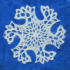 a white crocheted snowflake on a blue background