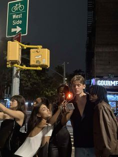 a group of people standing on the side of a road next to a traffic light