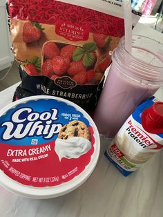 yogurt, ice cream and strawberries are sitting on a counter top next to a bag of whip cream