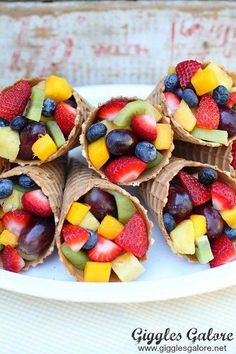 four cones filled with fruit on top of a white plate