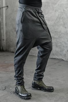 "DISTORTED ANTHRACITE DROPPED CROTCH TRACK PANTS WITH ELASTIC WAISTBAND __ELASTIC WAISTBAND WITH DRAWSTRING __J SHAPED LEGS __2 FRONT POCKETS __2 REAR BONDED POCKETS __ASYMMETRICAL HIDDEN FRONT CLOSURE model__ chest 103 (40.5\"), waist 77 (30.3\"), hips 96 (37.8\"), biceps 35 (13.8''), height 180 (5'11\"), kg 74 (163 lbs) model wears size S | color: anthracite with black matte tape fabric__ 100 cotton care__ delicate machine wash at 30 c wash inside out use cool iron do not tumble dry sizing__ s Fitted Tapered Leg Harem Pants With Pockets, Fitted Harem Pants With Pockets And Tapered Leg, Fitted Ankle-length Harem Pants With Pockets, Fitted Gray Pants With Hip Pockets, Fitted Gray Bottoms With Hip Pockets, Fitted Sweatpants With Pockets, Baggy Gray Pants With Hip Pockets, Black Fitted Drop Crotch Bottoms, Fitted Gray Pants With Side Pockets