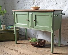 a green cabinet sitting on top of a wooden floor next to a potted plant