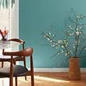 a dining room with blue walls and wooden chairs in front of a table that has flowers on it