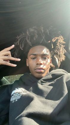 a man with dreadlocks sitting in the back seat of a car and pointing at something