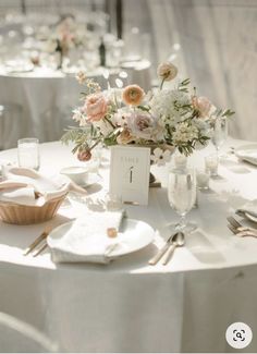 the table is set with white linens and floral centerpieces for an elegant wedding reception