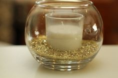 a candle is lit in a glass bowl filled with sand