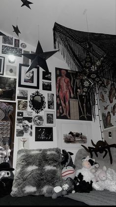 a bedroom with many pictures on the wall and stuffed animals hanging from the ceiling in front of it