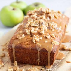 a loaf of bread with caramel drizzled on top and apples in the background