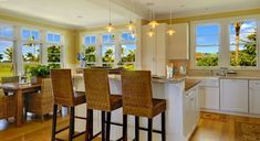 a large kitchen with lots of windows and bar stools next to the counter top