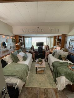 two women sitting on twin beds in a room with wood flooring and white walls