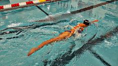 a man swimming in a pool with an orange swim suit