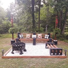 a wooden bench sitting on top of a lush green field next to a fire pit