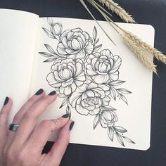 a woman's hand with black nail polish on top of a drawing of flowers