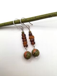 An earthy forest-inspired bohemian pair of silver dangle earrings; crafted with stainless steel French hooks, 4 mm polished unakite stone, brown sea glass, and a beautiful polished green unakite stone. *Handmade by me, one of a kind. *Length: 6 cm *Diameter of largest stone: 10 mm *Crafted with silver stainless steel hypoallergenic hooks.  Nickel free. Click on the link below if you would like to see more artisan jewelry and unique artwork! https://www.etsy.com/shop/CailinCreatesCo I try my best to accurately portray the details in all of my jewelry. Please note that colors may vary due to lighting conditions, camera settings, and variations in computer monitor or phone display settings. If you have any questions regarding any items I have available, please do not be afraid to reach out! Adjustable Earthy Dangle Earrings, Earthy Dangle Earrings With Ear Wire, Bohemian Amber Drop Earrings, Handmade Amber Bohemian Earrings, Bohemian Amber Earrings With Ear Wire, Handmade Bohemian Amber Earrings, Earthy Drop Earrings With Natural Stones, Earthy Style Drop Earrings With Matching Set, Bohemian Amber Dangle Earrings