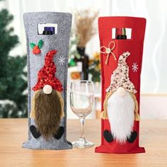 two wine bags decorated with gnomes and snowmen are sitting on a table next to a glass of wine