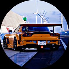 an orange sports car parked in front of wind mills