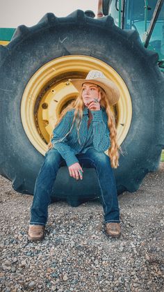 a woman sitting in front of a tractor tire