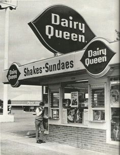 an old black and white photo of a man standing in front of a dairy queen store