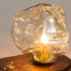 a glass lamp sitting on top of a wooden table next to a small light bulb