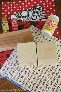 some wood blocks and glue are sitting on a piece of paper with mickey mouse designs