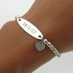 a close up of a person's arm wearing a bracelet with a heart charm