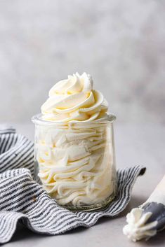 a glass jar filled with whipped cream on top of a towel next to a spoon