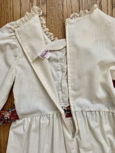 "Medium Weight Cotton Linen Blend Tiered Maxi Dress with bands of floral cotton and maroon ribbon trim Front has cream colored lace and cream lacing Zipper up the back Short tie ends that go around to the back Label says \"The Beaux Age\" Excellent Vintage Condition Fits like an XS **BUST 32 inches **HIGH WAIST 28 inches **LOW WAIST. 36 inches **HIPS 36 inches **SHOULDER DOWN TO BOTTOM 48 inches **SHOULDER TO SHOULDER (BACK) 13 inches ✩ MEASURING YOURSELF ✩ Use a dressmaker's tape measure, which Beige Cotton Prairie Dress For Daywear, Vintage Cotton Dress With Yoke Detail, Vintage Cream Cotton Dress, Cream Peasant Cotton Dress, Cream Cotton Peasant Dress, Fitted Beige Cotton Vintage Dress, Cottagecore Cream Cotton Prairie Dress, Cottagecore Cream Prairie Dress, Vintage Cotton Yoke Dress