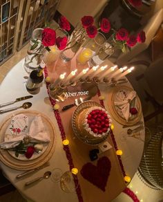 the table is set for valentine's day with candles and flowers on it,