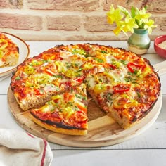 a pizza sitting on top of a wooden cutting board next to a plate with a slice missing