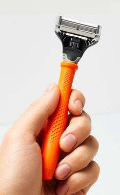 a person holding an orange razor in their hand